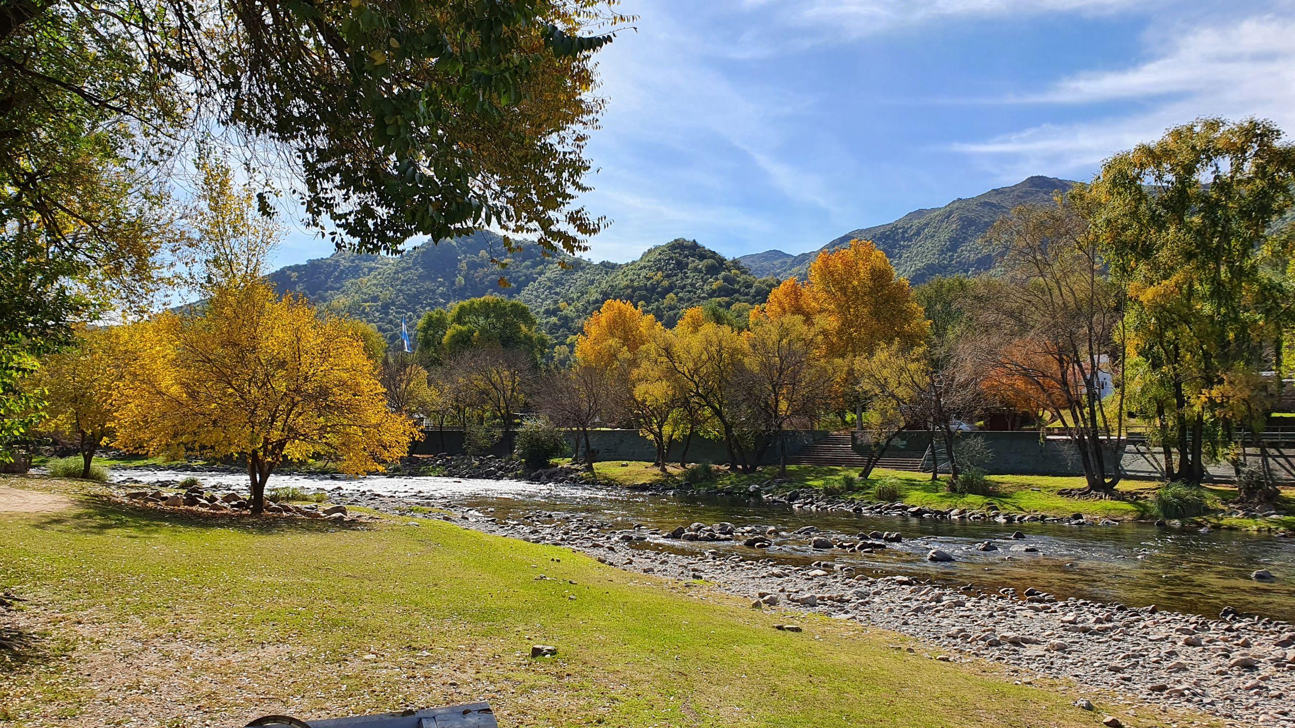 Río con colores otoñales y montañas de fondo